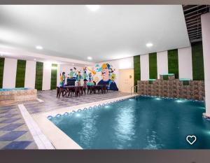 a swimming pool in a room with a table and a painting at Hotel Indo Tiger by RawatHospitality in Tembhuida