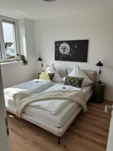 a white bedroom with a large white bed with pillows at Alte Feuerwache "nur wenige Minuten von Freiburg" in Hugstetten