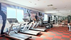 a gym with tread machines and a mural on the wall at Sunday Hotel Al Barsha Dubai Mall of the Emirates Formerly Grand Excelsior Al barsha in Dubai