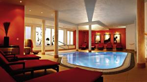 a large swimming pool in a room with red walls at Hotel Alpina nature-wellness in Wenns