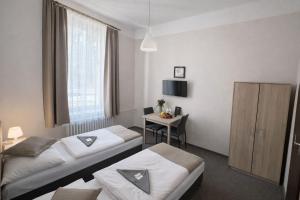 a hotel room with two beds and a desk at Hotel Hůrka in Pardubice
