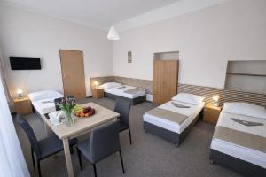 a hospital room with beds and a table with a bowl of fruit at Hotel Hůrka in Pardubice