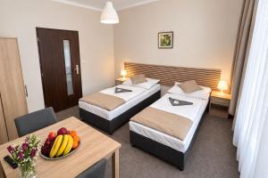 a hotel room with two beds and a table with a bowl of fruit at Hotel Hůrka in Pardubice