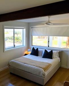 a bedroom with a large bed with two windows at Archy's on the Lake in Burrill Lake