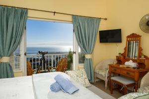 a bedroom with a bed and a desk and a window at Albatross Guest House in Simonʼs Town