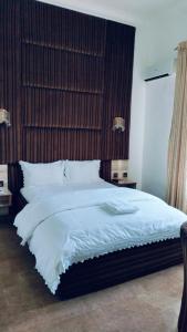 a bedroom with a large white bed with a wooden headboard at Meglams Hotel and Suite in Yenagoa +4 photos
