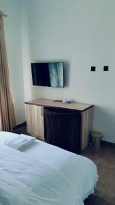 a bedroom with a bed and a desk with a television at Meglams Hotel and Suite in Yenagoa