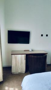 a room with a desk with a television on a wall at Meglams Hotel and Suite in Yenagoa