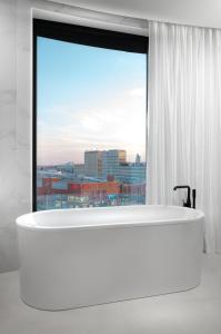 a large white tub in a room with a window at Clarion Congress Hotel Brno in Brno