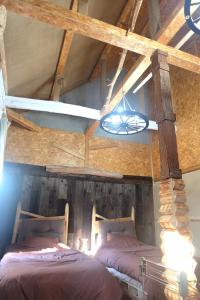 two beds in a room with a ceiling with beams at はじまりの宿 ディール in Tsumagoi