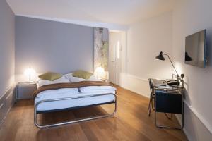 a bedroom with a bed and a desk and a television at Baseltor Hotel & Restaurant in Solothurn