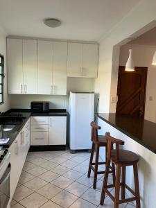 a kitchen with a white refrigerator and two bar stools at Panamá 90 - 21 - Região Central in Poços de Caldas