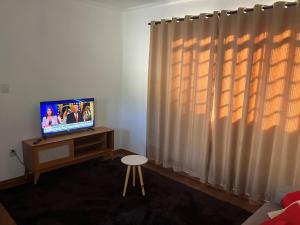 a living room with a television and a curtain at Panamá 90 - 21 - Região Central in Poços de Caldas