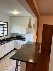 a kitchen with white cabinets and a black counter top at Panamá 90 - 21 - Região Central in Poços de Caldas +14 photos
