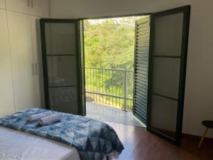 a bedroom with a bed and a door to a balcony at Panamá 90 - 21 - Região Central in Poços de Caldas