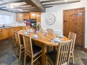 a dining room table with chairs and a clock on the wall at Denham in Glaisdale
