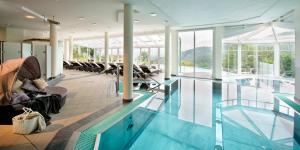 a pool in a hotel with chairs and a swimming pool at das kappel wein gut hotel in Kitzeck im Sausal