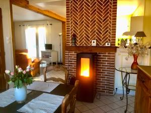 a living room with a table and a brick fireplace at Gîte Margot in Vacqueriette