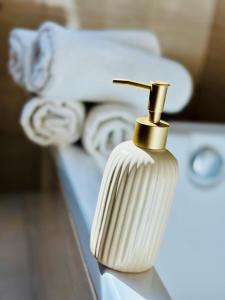 a white perfume bottle with a gold nozzle on a table at Studio apartman in Kőszeg +35 photos