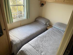 two beds in a small room with a window at Bridge Farm Caravan in Buxton