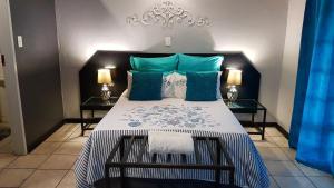 a bedroom with a large bed with blue and green pillows at Siesta Guest House in Musina