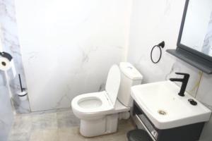 a bathroom with a white toilet and a sink at Maya Stays in Busia +11 photos