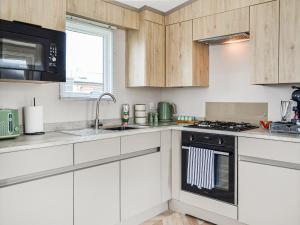 a kitchen with white cabinets and a stove top oven at Baywood View in East Heslerton