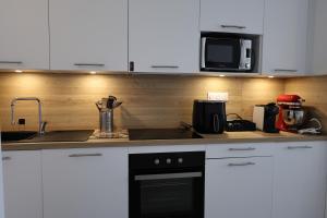 a kitchen with white cabinets and a black appliance at Casa di Daisy - T2 les pieds dans l'eau et piscine in Pianottoli-Caldarello +39 photos