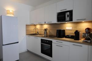a kitchen with white cabinets and a sink and a microwave at Casa di Daisy - T2 les pieds dans l'eau et piscine in Pianottoli-Caldarello