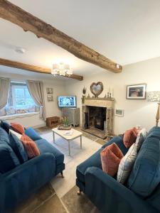 a living room with two blue couches and a fireplace at Bents Holiday Cottage, Views & Parking for two cars in Oxenhope