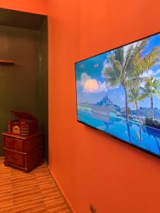 a flat screen tv hanging on an orange wall at Hôtel YABISSO in Lomé