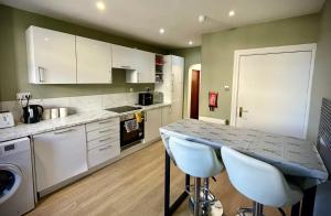 a kitchen with white cabinets and a counter with stools at Stag and Barrel in Elgin