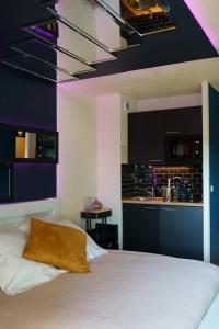 a bedroom with a white bed and a kitchen at love room, sauna et balnéo in Perros-Guirec