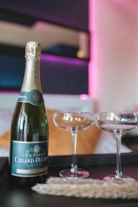 a bottle of champagne and two glasses on a table at love room, sauna et balnéo in Perros-Guirec