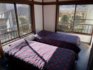 two beds sitting in a room with windows at コテージ鹿留スマプロハウス ペットと泊まれる一棟貸し 富士急まで20分 2階建て3LDK最大8名 Wi-Fi完備 in Tsuru 