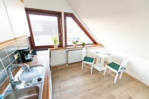 a kitchen with a sink and a desk with two chairs at Charmante Ferienwohnung mit sonniger Loggia in Celle