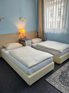 two beds in a room with a lamp on a table at Hotel Jägerhof in Wiesbaden