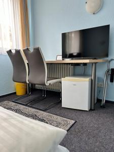 a room with a desk with a tv and two chairs at Hotel Jägerhof in Wiesbaden
