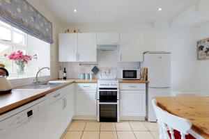 a kitchen with white appliances and a wooden table at Pant Glas in Penmaen-mawr +10 photos