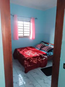 a bedroom with a bed with red sheets and a window at Chambre et apparts meublés, Yaoundé - FOKOU EMANA in Yaoundé
