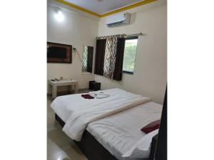 a bedroom with a large white bed and a window at Green Leaf Mini Resort in Mahabaleshwar
