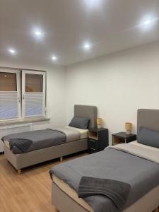 ein Schlafzimmer mit zwei Betten und zwei Fenstern in der Unterkunft WeserZeit Apartment in Bodenwerder