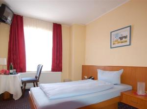 Schlafzimmer mit einem Bett, einem Tisch und einem Fenster in der Unterkunft Hotel Hohenzollern in Schleswig