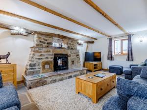 a living room with a stone fireplace and blue chairs at Barn View in Clay Cross