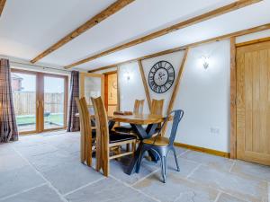 a dining room with a table and chairs and a clock on the wall at Barn View in Clay Cross