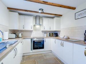 a kitchen with white cabinets and a sink at Barn View in Clay Cross +16 photos