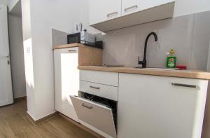 a kitchen with white cabinets and a sink at Apartmani Antonela in Seline