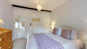 a bedroom with a white bed and a chandelier at Pant Glas in Penmaen-mawr