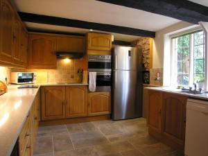 a kitchen with wooden cabinets and a stainless steel refrigerator at West Wing- Ukc4914 in Timberscombe