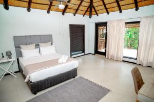 a bedroom with a bed and a desk and windows at The View Guesthouse in Nelspruit +44 photos